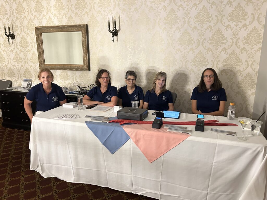 Picture of 5 women sitting at a registration table at an event